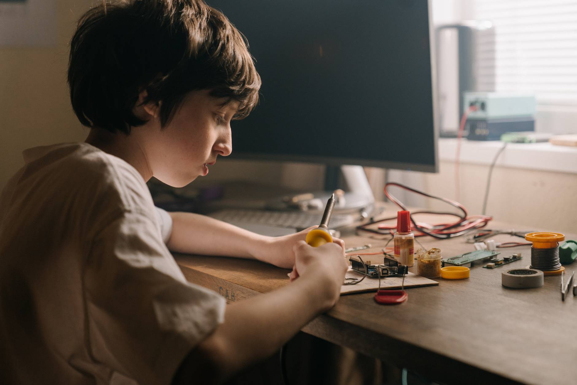 boy in white shirt holding yellow plastic toy